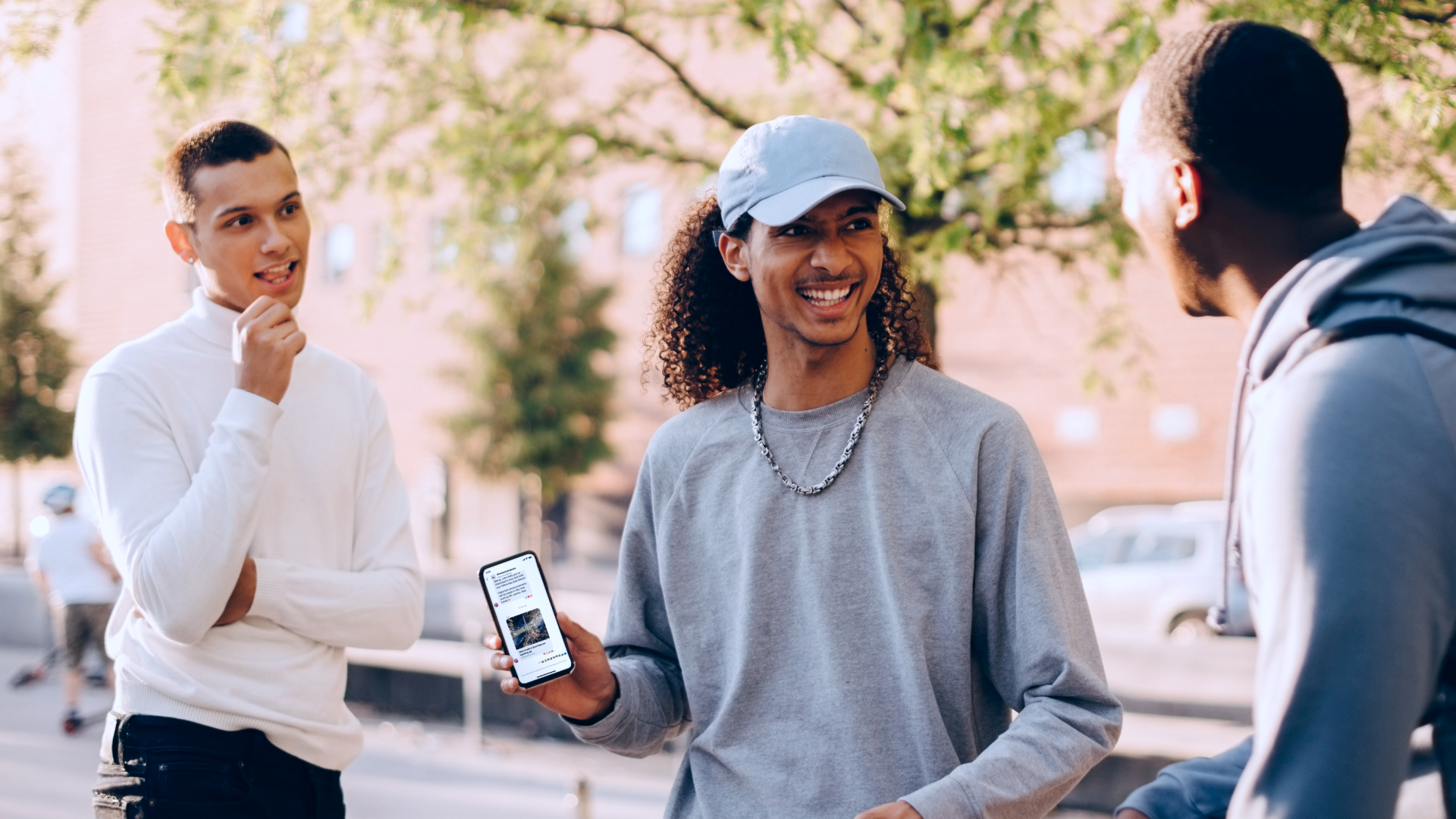 Image showing three people smiling, with one holding a phone featuring a Community Chat.